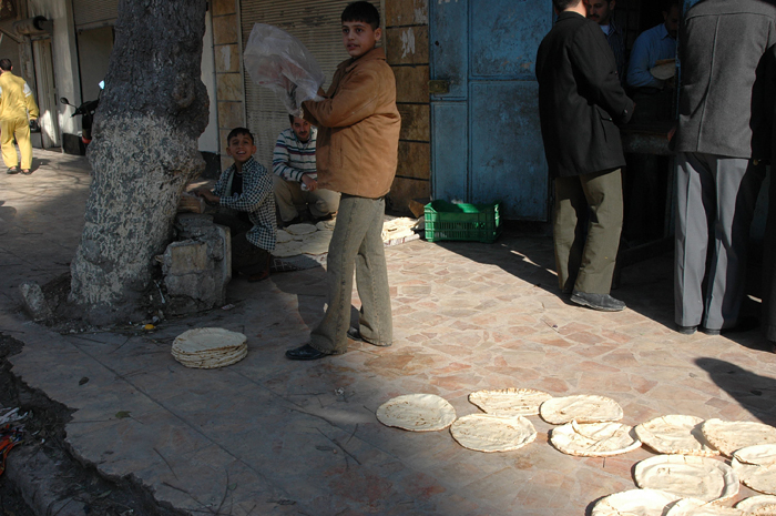 Сирийские подростки раскладывают хлеб на тротуаре